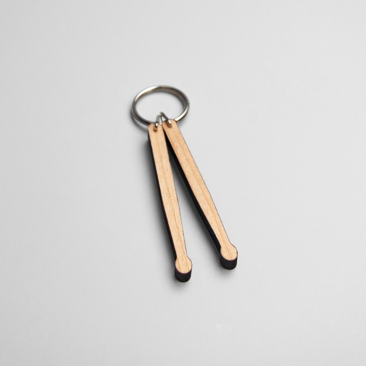 Houten sleutelhanger in de vorm van twee kleine drumstokken.
